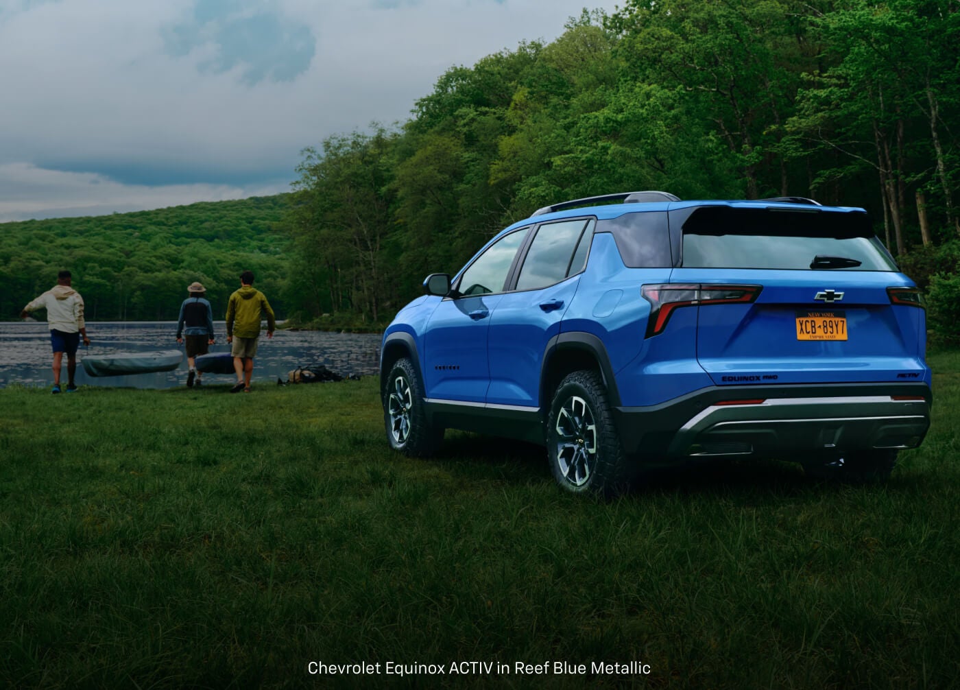Rear three-quarter view of a Chevrolet Equinox ACTIV in Blue with three people carrying a kayak.