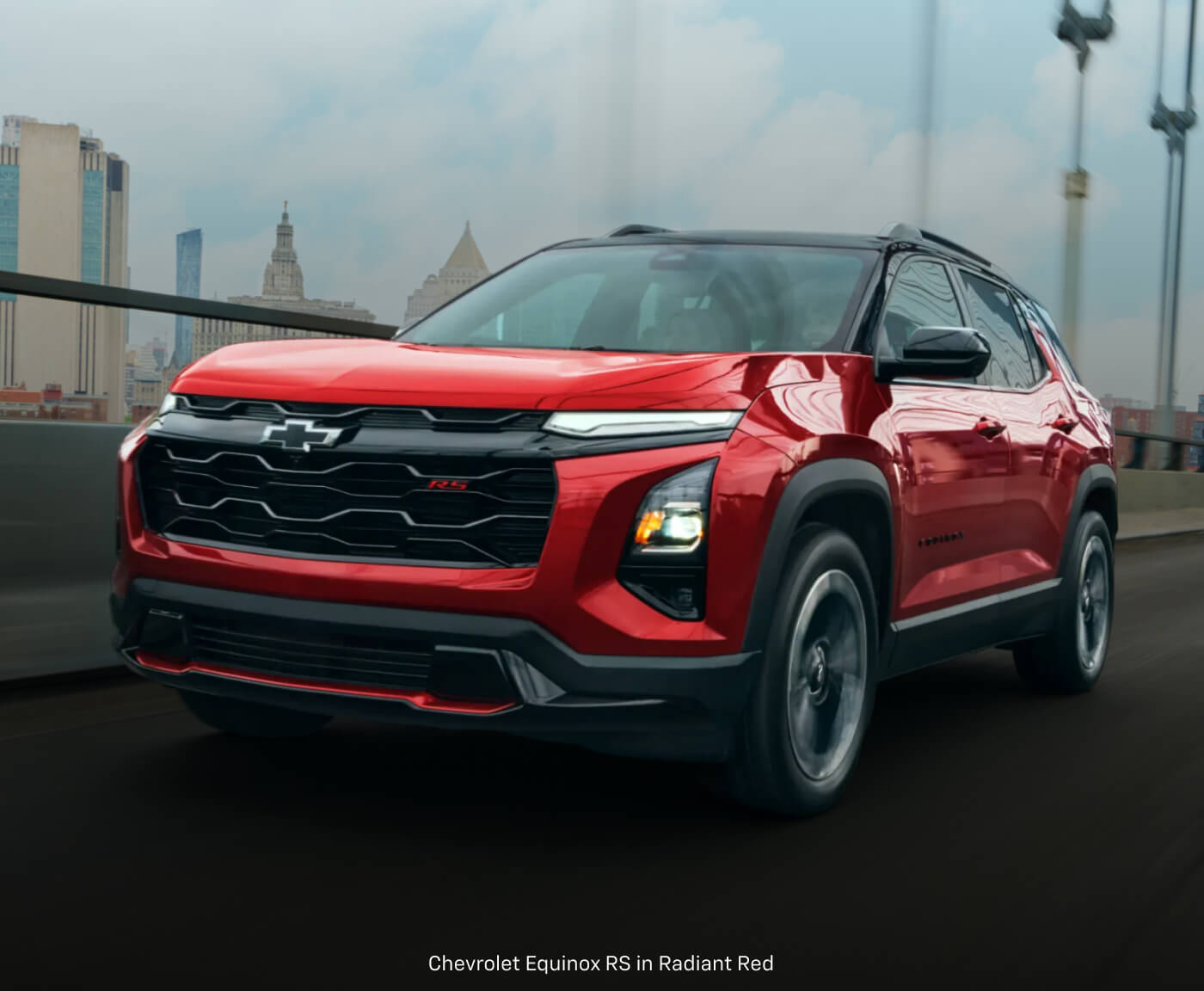 Three-quarter front view of a Chevrolet Equinox RS in Red driving across an urban bridge.