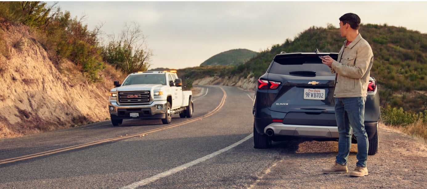 Rear-three-quarter view of a Chevrolet Blazer waiting for an oncoming GMC Sierra tow truck.
