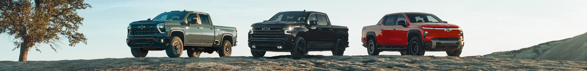 Chevrolet Silverado 1500, Tahoe, and Equinox EV on a sandy hill