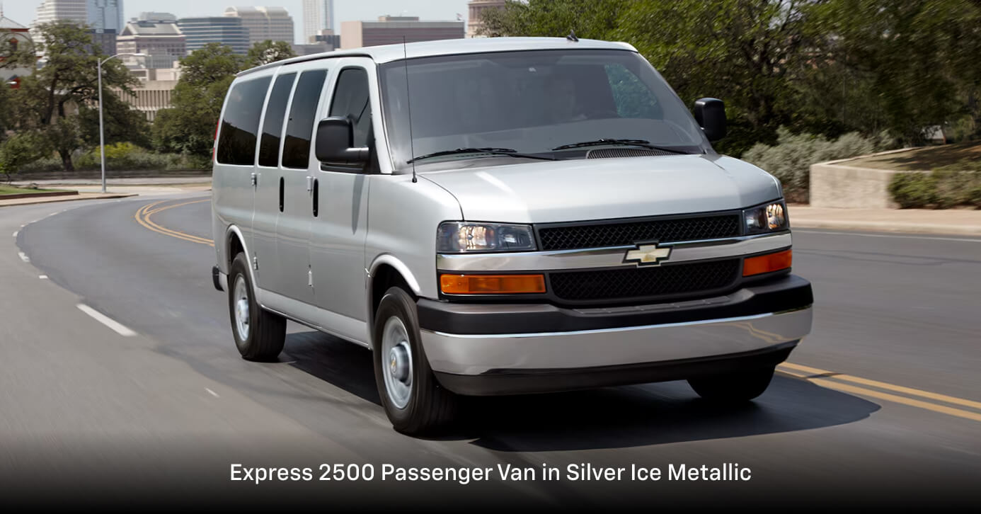 2026 Chevrolet Express 2500 Passenger Van in Silver Ice Metallic driving on a curving city road.