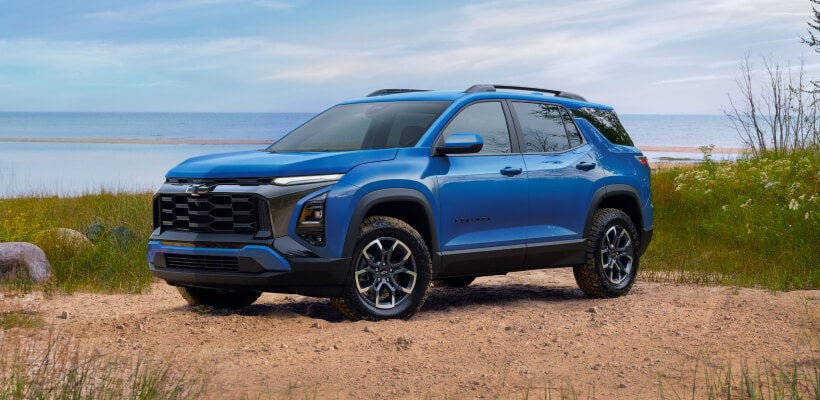 Front three-quarter view of blue Chevrolet Equinox parked on a dirt trail near a lake shore.
